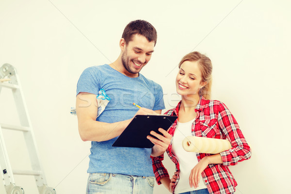 smiling couple with clipboard and wallpaper roll Stock photo © dolgachov