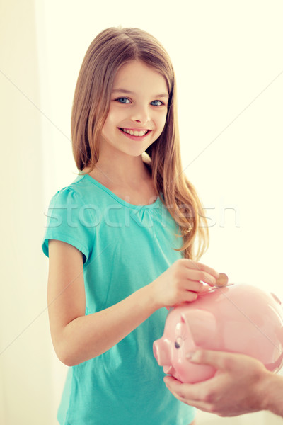 smiling little girl putting coin into piggy bank Stock photo © dolgachov