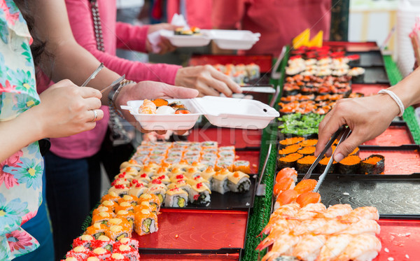 close up of hands with tongs taking sushi Stock photo © dolgachov