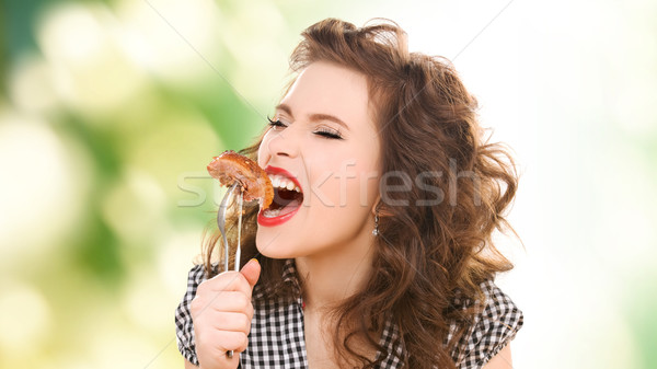 Stock photo: hungry young woman eating meat on fork over green