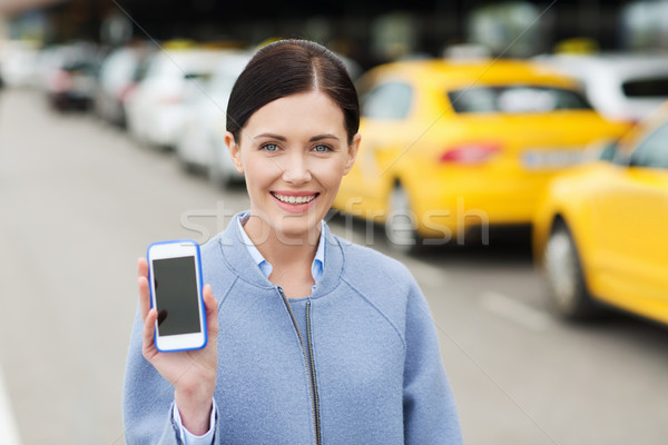 smiling woman showing smartphone over taxi in city Stock photo © dolgachov