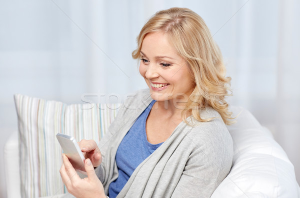 Stock photo: smiling woman with smartphone texting at home