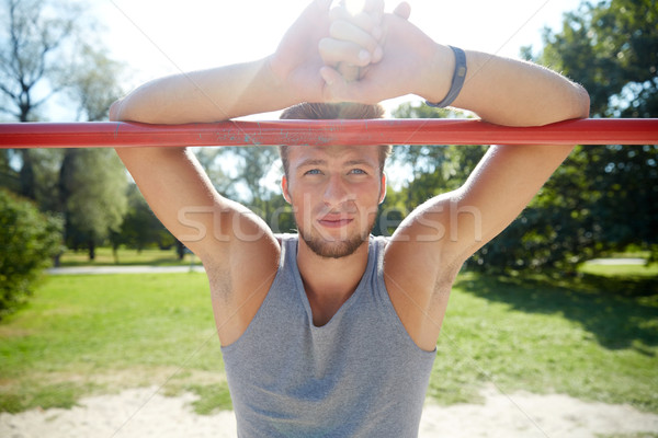 young man exercising on horizontal bar outdoors Stock photo © dolgachov