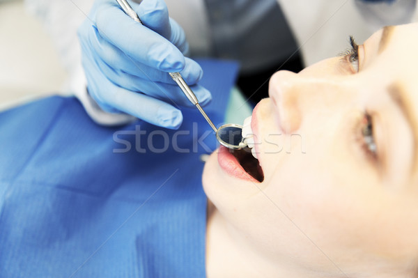 close up of dentist examining female patient teeth Stock photo © dolgachov