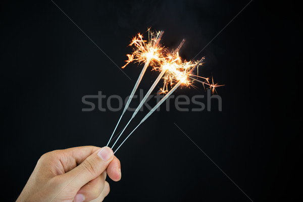 hand holding sparklers over black background Stock photo © dolgachov