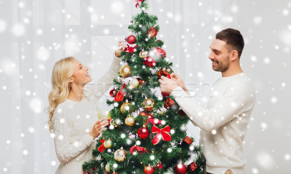 happy couple decorating christmas tree at home Stock photo © dolgachov