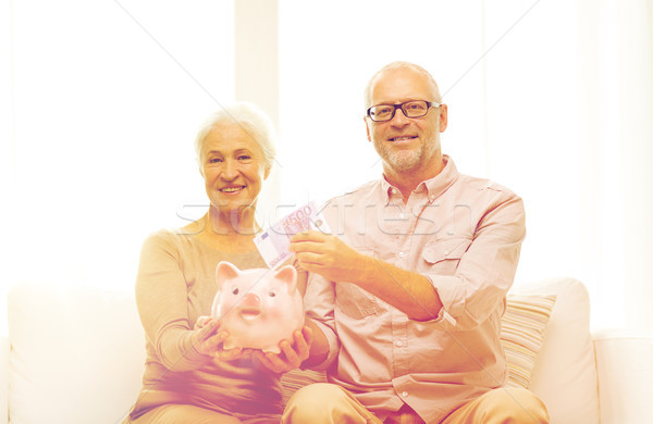 senior couple with money and piggy bank at home Stock photo © dolgachov