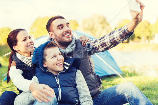 family with smartphone taking selfie at campsite Stock photo © dolgachov