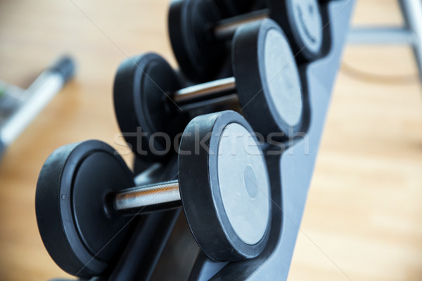 Stock photo: close up of dumbbells and sports equipment in gym