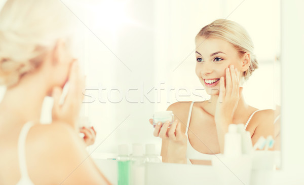 Heureux femme crème visage salle de bain [[stock_photo]] © dolgachov