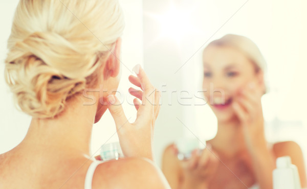 Közelkép nő jelentkezik arckrém fürdőszoba szépség Stock fotó © dolgachov