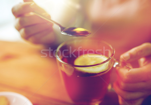 close up of woman adding honey to tea with lemon Stock photo © dolgachov