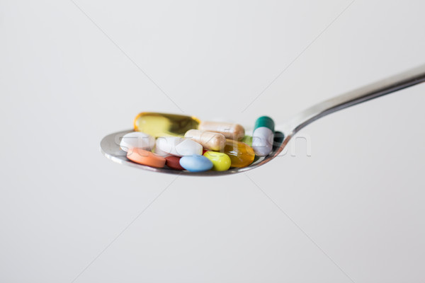 Stock photo: different pills and capsules of drugs on spoon