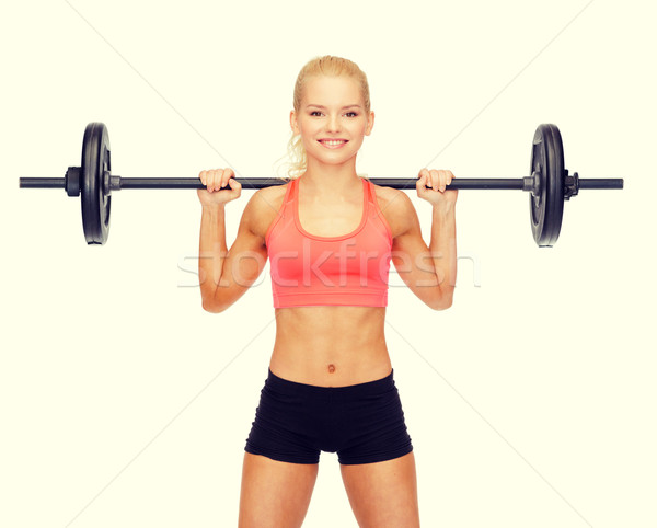 Stock photo: smiling sporty woman exercising with barbell