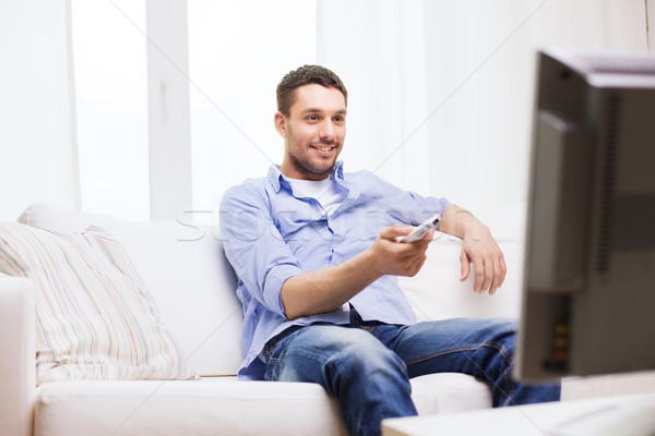 smiling man with tv remote control at home Stock photo © dolgachov