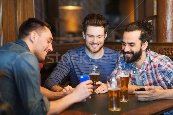 Stockfoto: Mannelijke · vrienden · smartphones · drinken · bier · bar