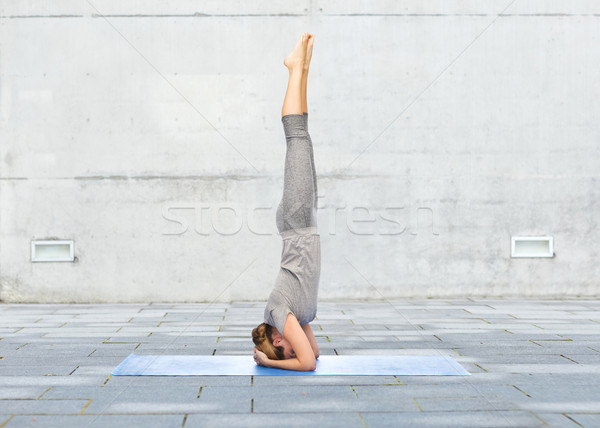 woman making yoga in headstand pose on mat Stock photo © dolgachov