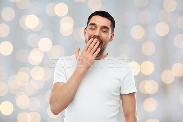 yawning man over holidays lights background Stock photo © dolgachov
