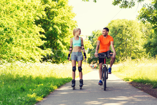 happy couple with roller skates and bicycle riding Stock photo © dolgachov