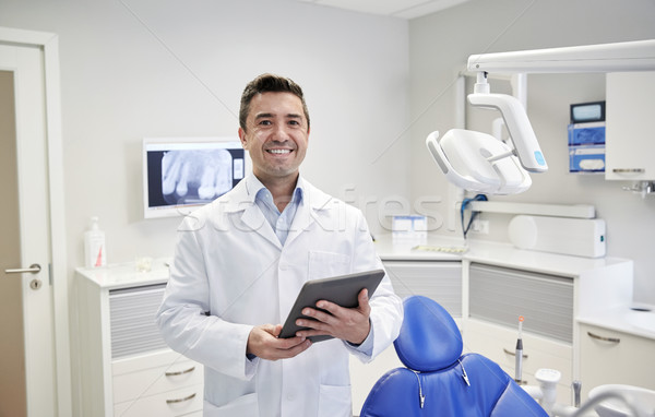 happy male dentist with tablet pc at dental clinic Stock photo © dolgachov