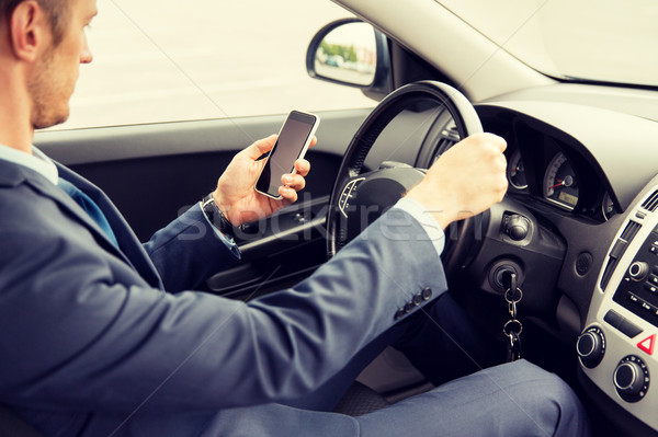 Stock photo: close up of man with smartphone driving car