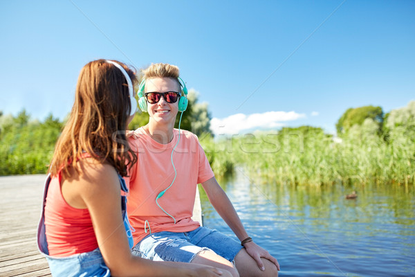 happy teenage couple with earphones on river berth Stock photo © dolgachov