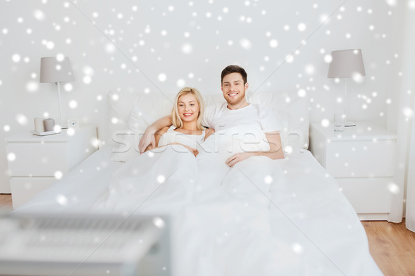 happy couple lying in bed at home and watching tv Stock photo © dolgachov