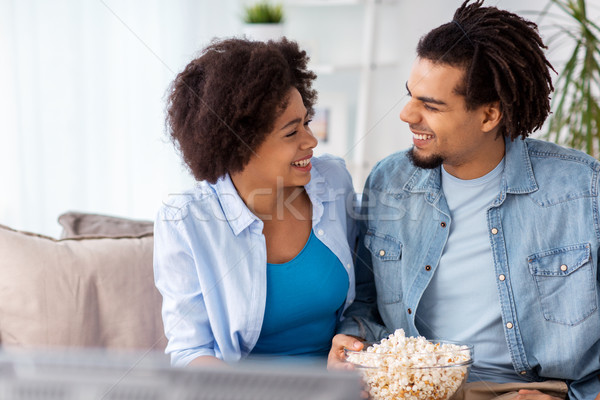 smiling couple with popcorn watching tv at home Stock photo © dolgachov