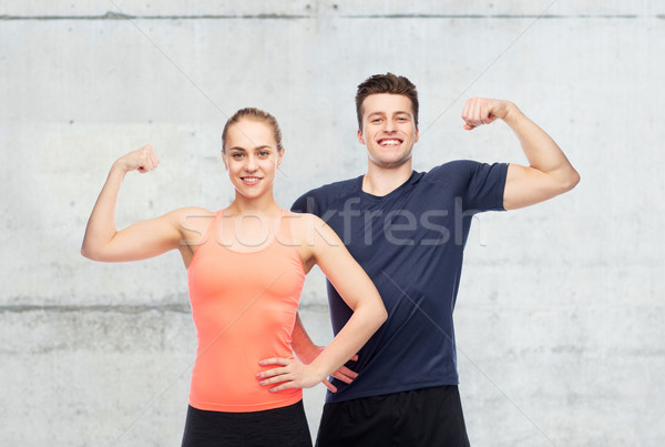 Stock photo: happy sportive man and woman showing biceps power