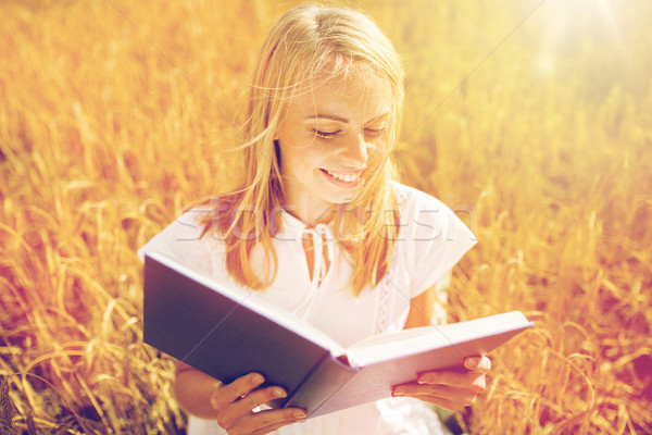 Stock photo: smiling young woman reading book on cereal field