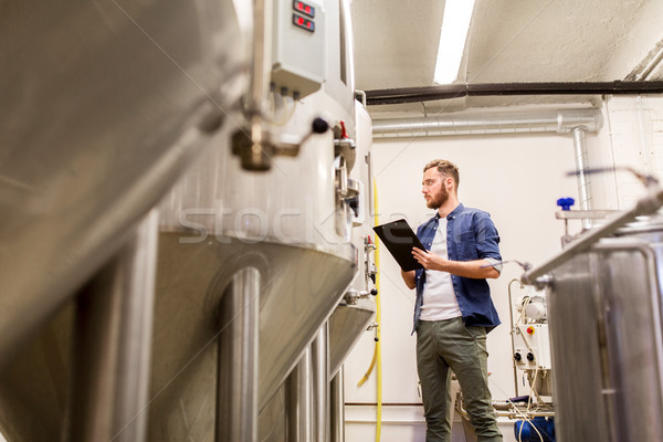 man with clipboard at craft brewery or beer plant Stock photo © dolgachov