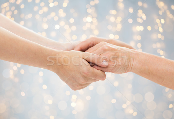 close up of senior and young woman holding hands Stock photo © dolgachov