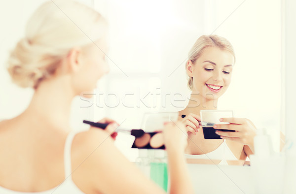 Stock photo: woman with makeup brush and foundation at bathroom