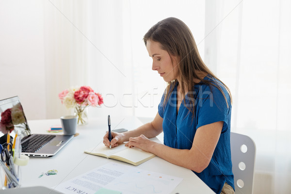 woman writing to notebook at office Stock photo © dolgachov