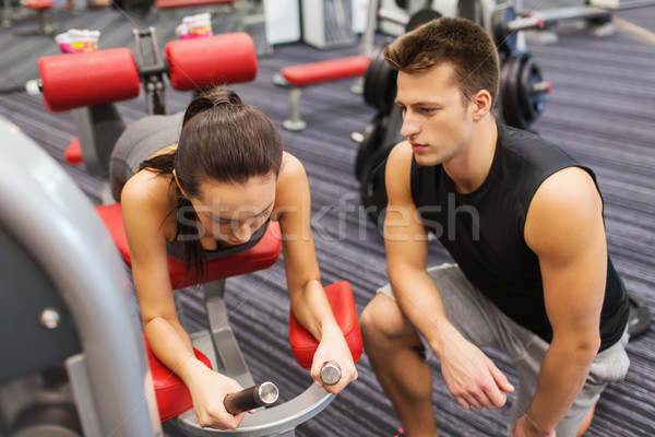young woman with trainer exercising on gym machine Stock photo © dolgachov