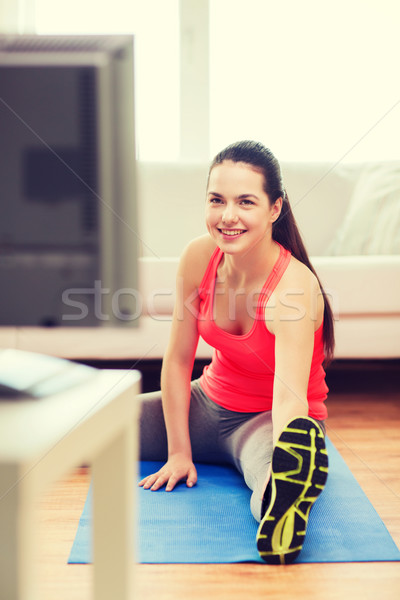 smiling teenage girl streching on floor at home Stock photo © dolgachov