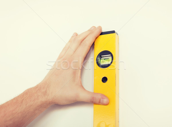 close up of male with spirit level mesuring wall Stock photo © dolgachov