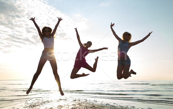 happy female friends dancing and jumping on beach Stock photo © dolgachov