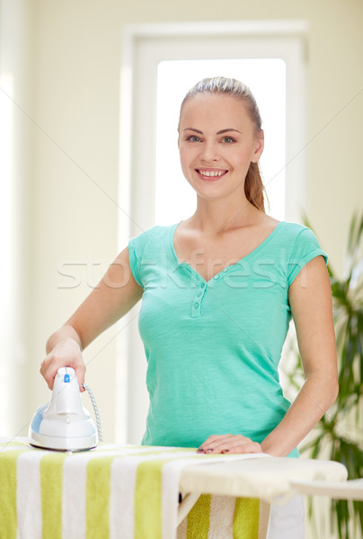 happy woman with iron and ironing board at home Stock photo © dolgachov