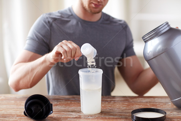 close up of man with protein shake bottle and jar Stock photo © dolgachov