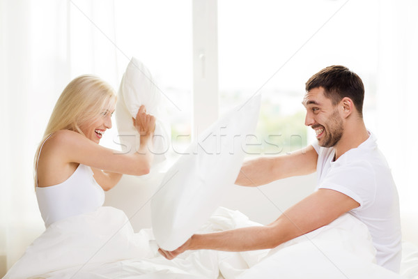 Szczęśliwy para pillow fight bed domu ludzi Zdjęcia stock © dolgachov