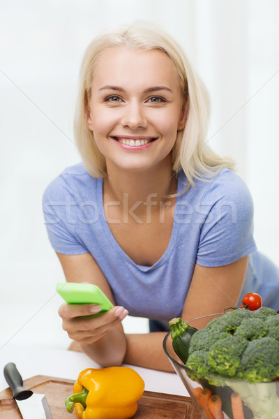 Femme souriante smartphone cuisson légumes nourriture végétarienne [[stock_photo]] © dolgachov