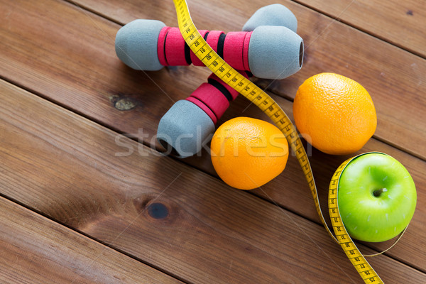 Stock photo: close up of dumbbell, fruits and measuring tape