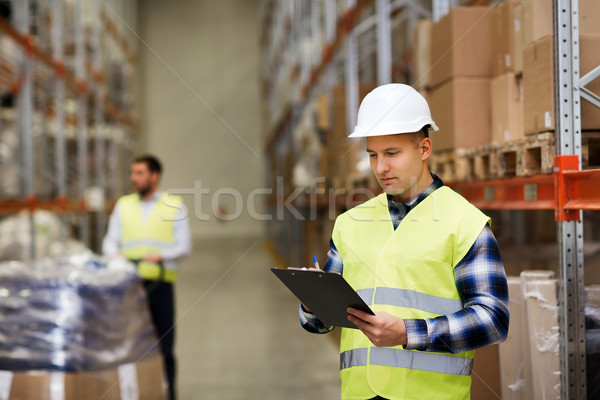 man with clipboard in safety vest at warehouse Stock photo © dolgachov
