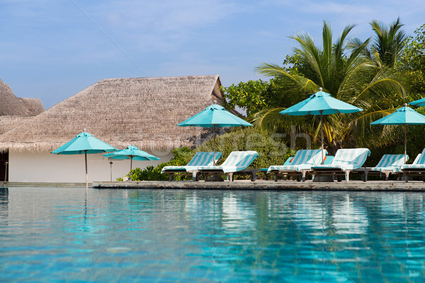 parasol and sunbeds by sea on maldives beach Stock photo © dolgachov