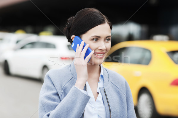 smiling woman with smartphone over taxi in city Stock photo © dolgachov
