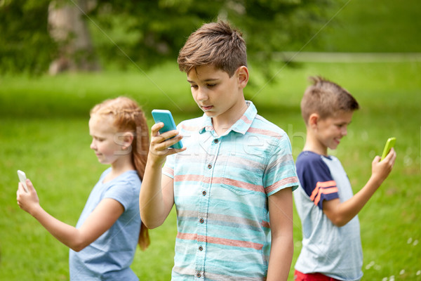 kids with smartphones playing game in summer park Stock photo © dolgachov