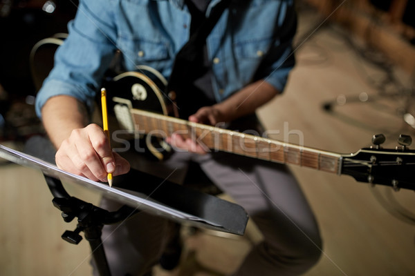 man with guitar writing to music book at studio Stock photo © dolgachov
