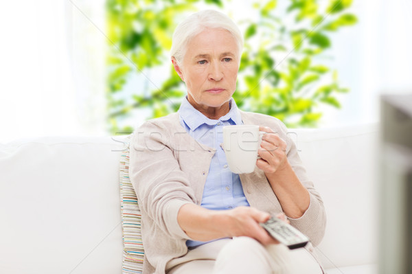 senior woman watching tv and drinking tea at home Stock photo © dolgachov