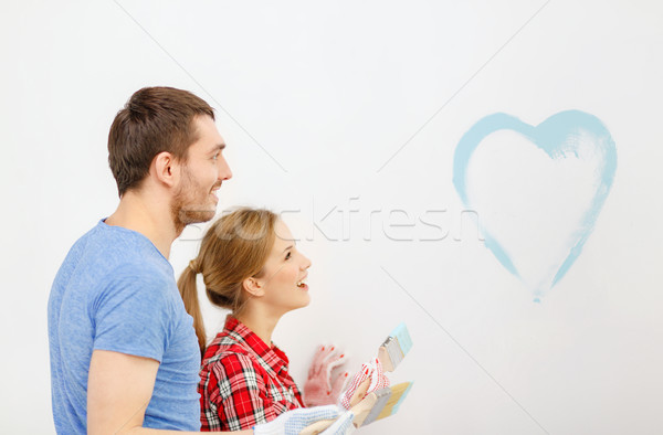 Stock photo: smiling couple painting small heart on wall